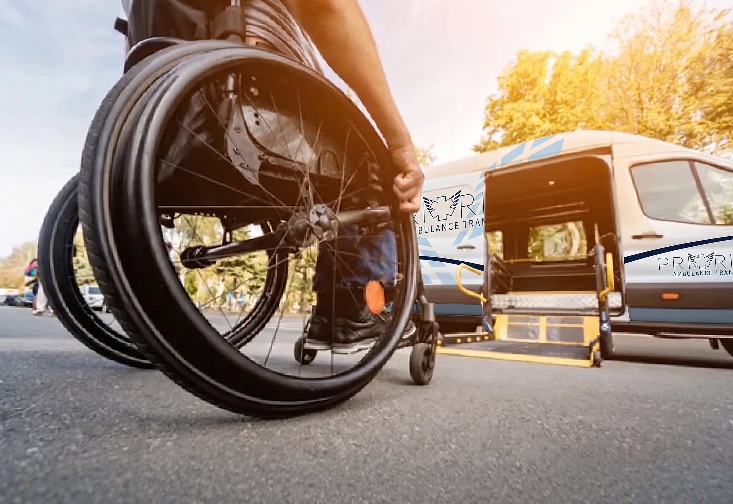 A wheelchair user being assisted into a Priority Ambulance Transfer wheelchair-equipped van.